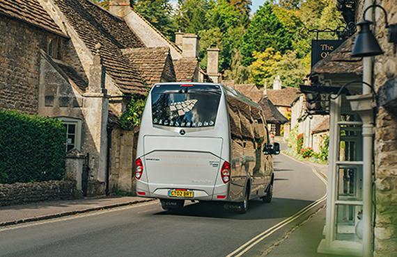 A tour bus travels down a road in a small town.